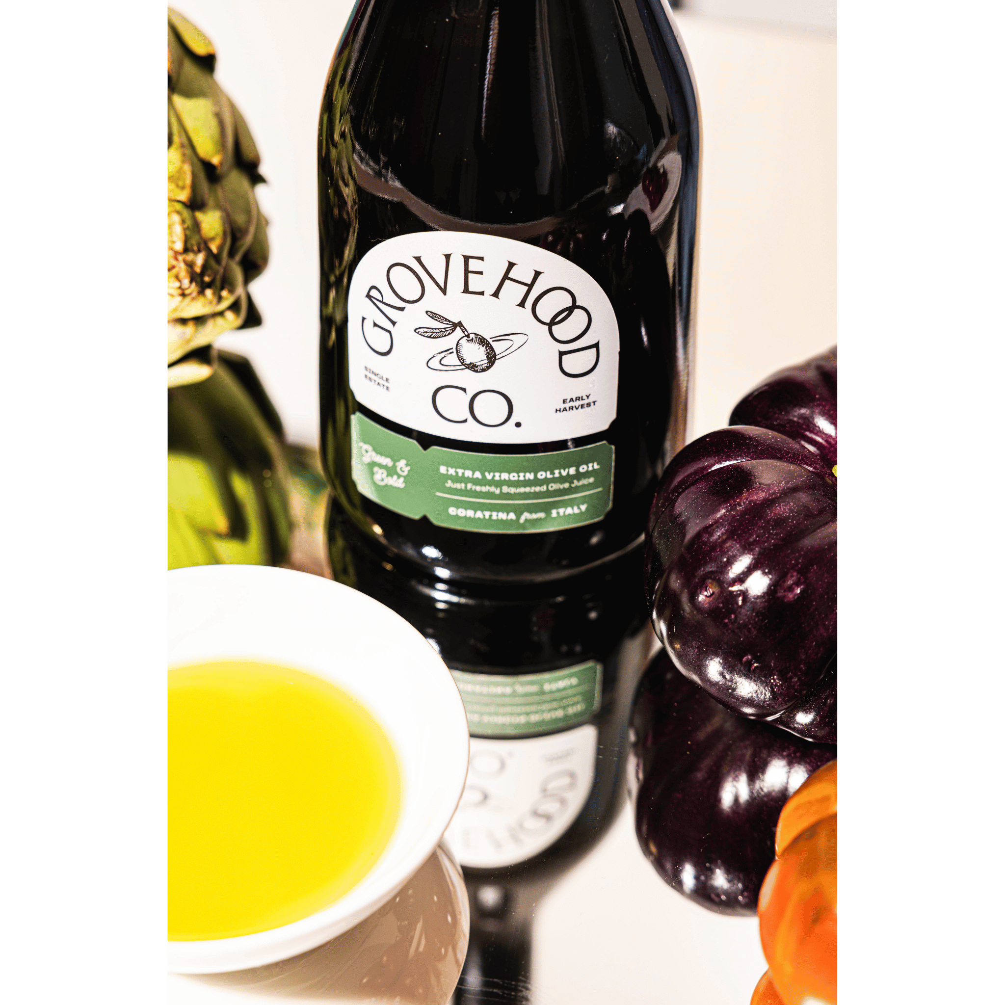 Grovehood Collective Italian extra virgin olive oil bottle at a table with tomatoes