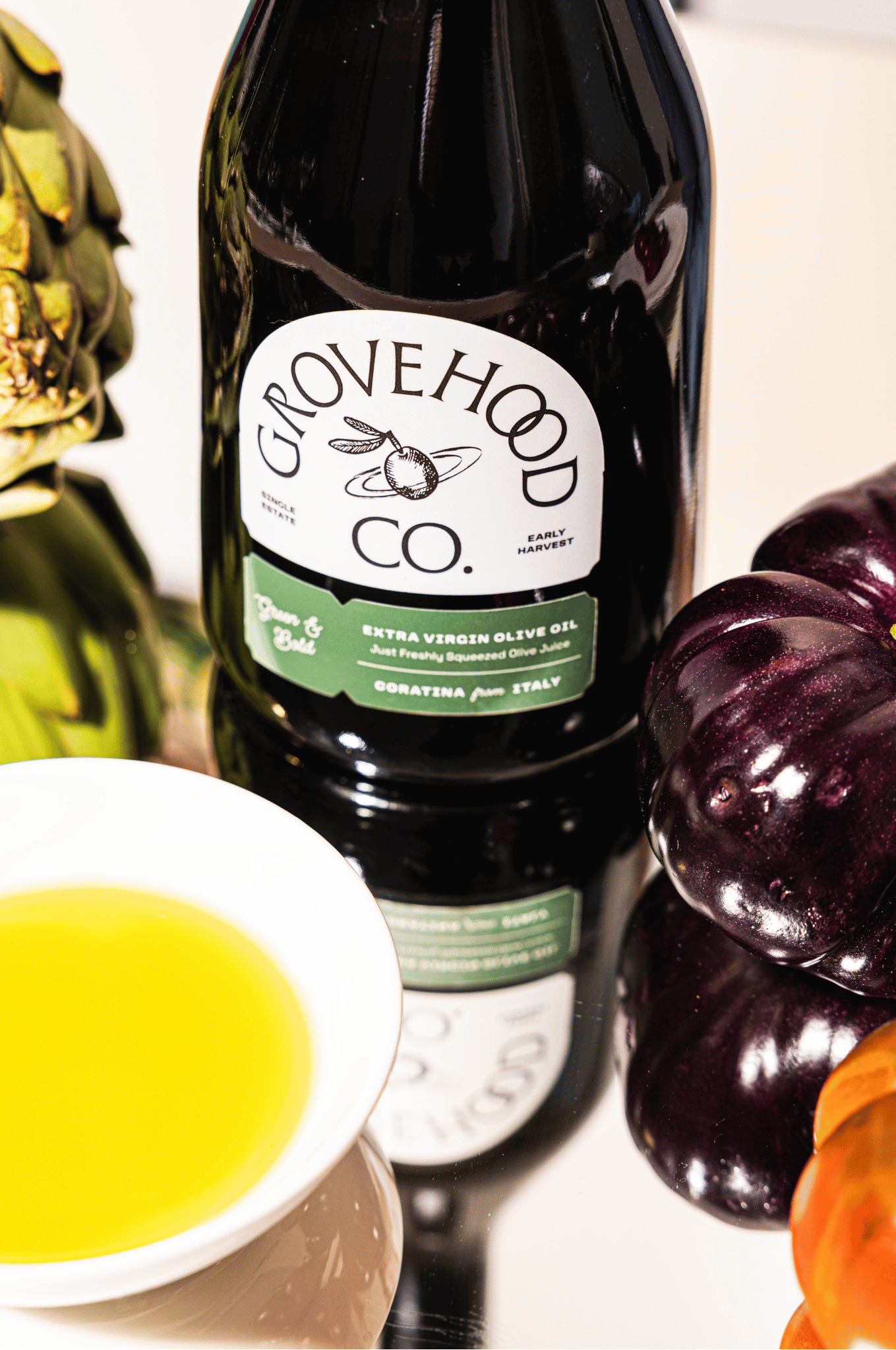 Grovehood Collective Italian extra virgin olive oil bottle at a table with tomatoes