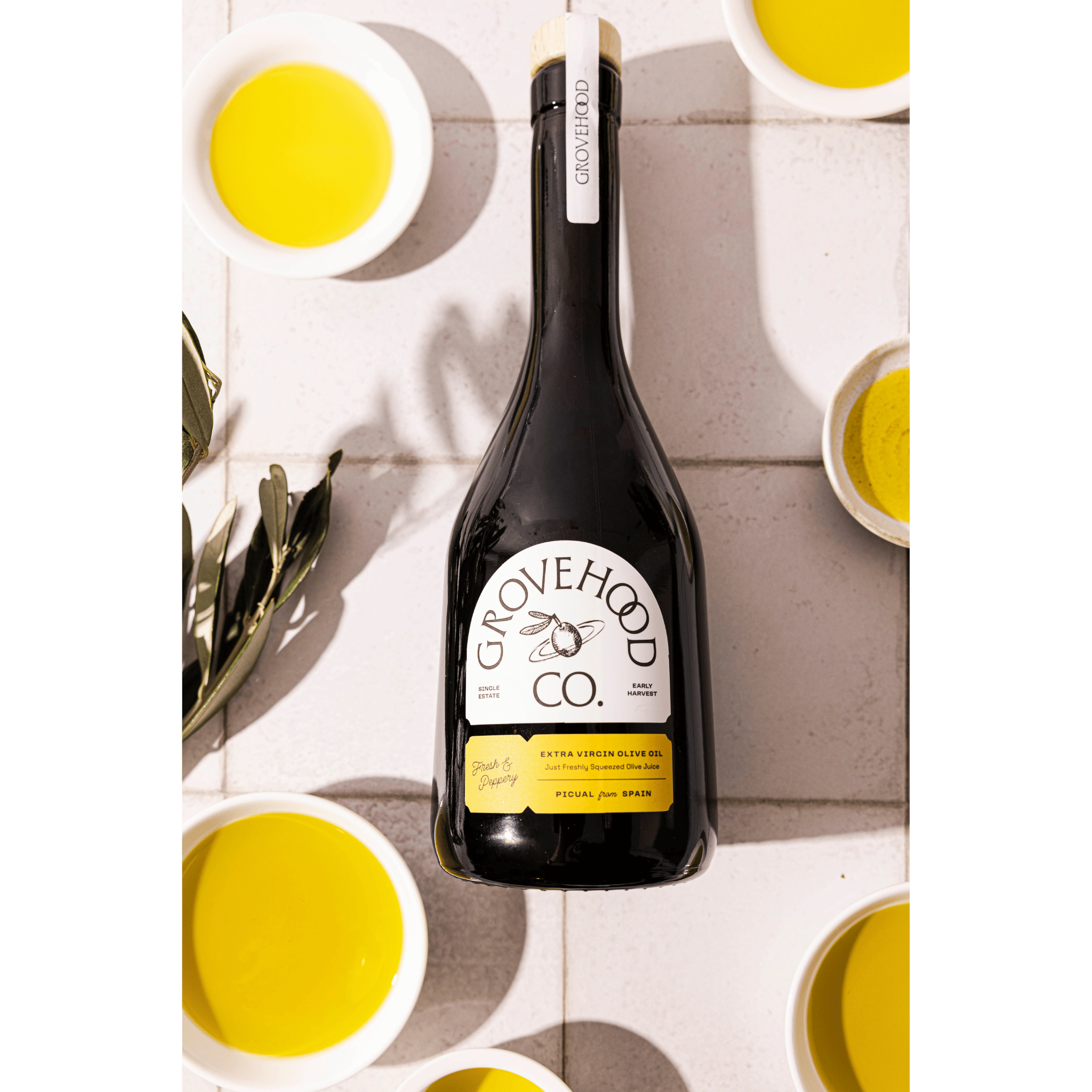 Grovehood Collective Spanish extra virgin olive oil bottle laid flat on a tile